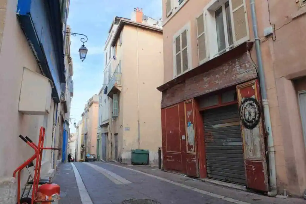 Authentic French small shop or taverna, locked, at antient narrow street with cosy yellow houses in the old town La Panier in Sunny Marseille in Mediterrian France
