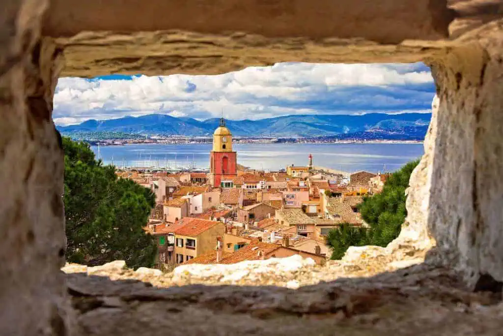 Saint Tropez village church tower and old rooftops view through stone window, famous tourist destination on Cote d Azur, Alpes-Maritimes department in southern France